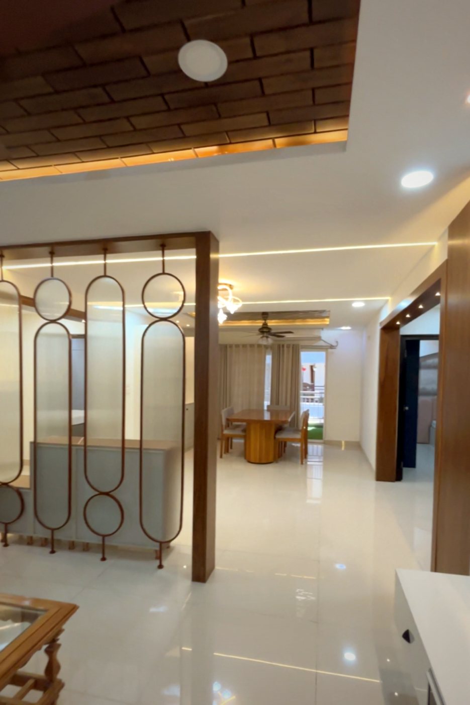 Living room with a wood-framed decorative partition and cove-lit false ceiling