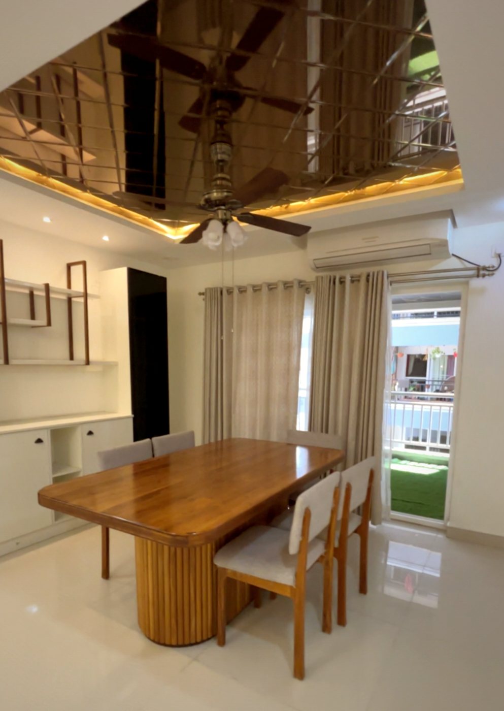 Dining room with a teak table and mirrored false ceiling, designed by Alegria Spaces in Hyderabad