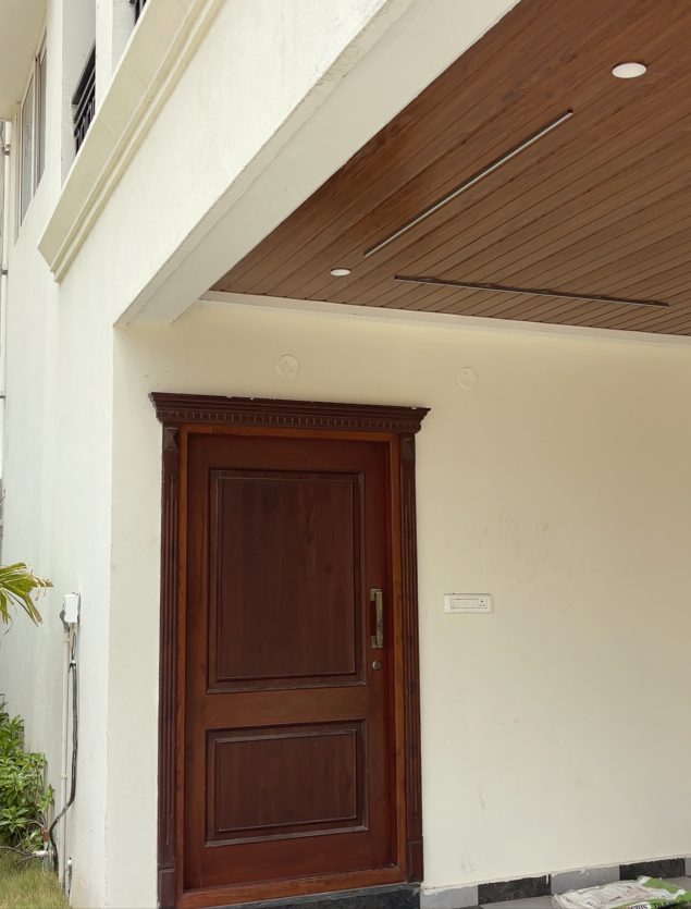 Solid wood main door with a carved frame at a villa entrance