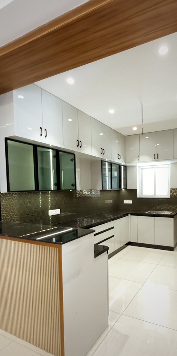 Modular kitchen with glossy white cabinets and a black granite counter