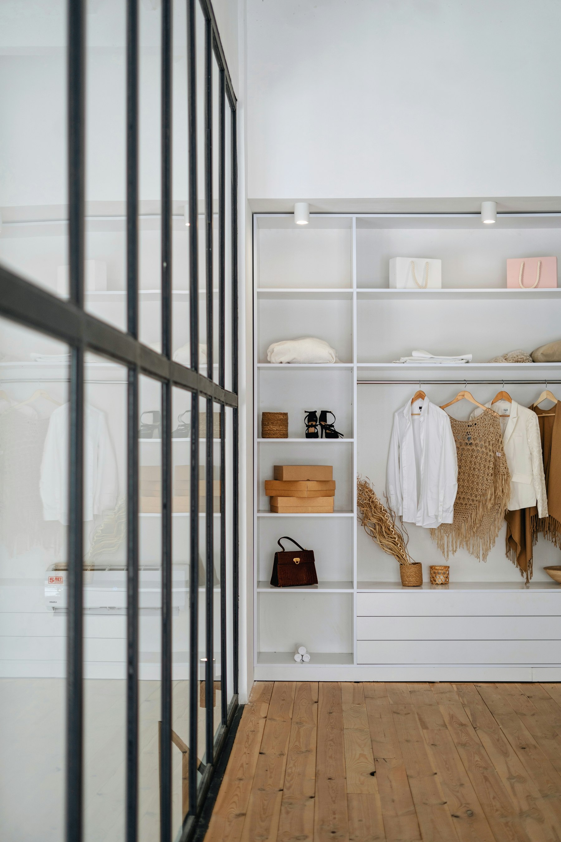 Walk-in wardrobe with open white shelving behind a glass partition