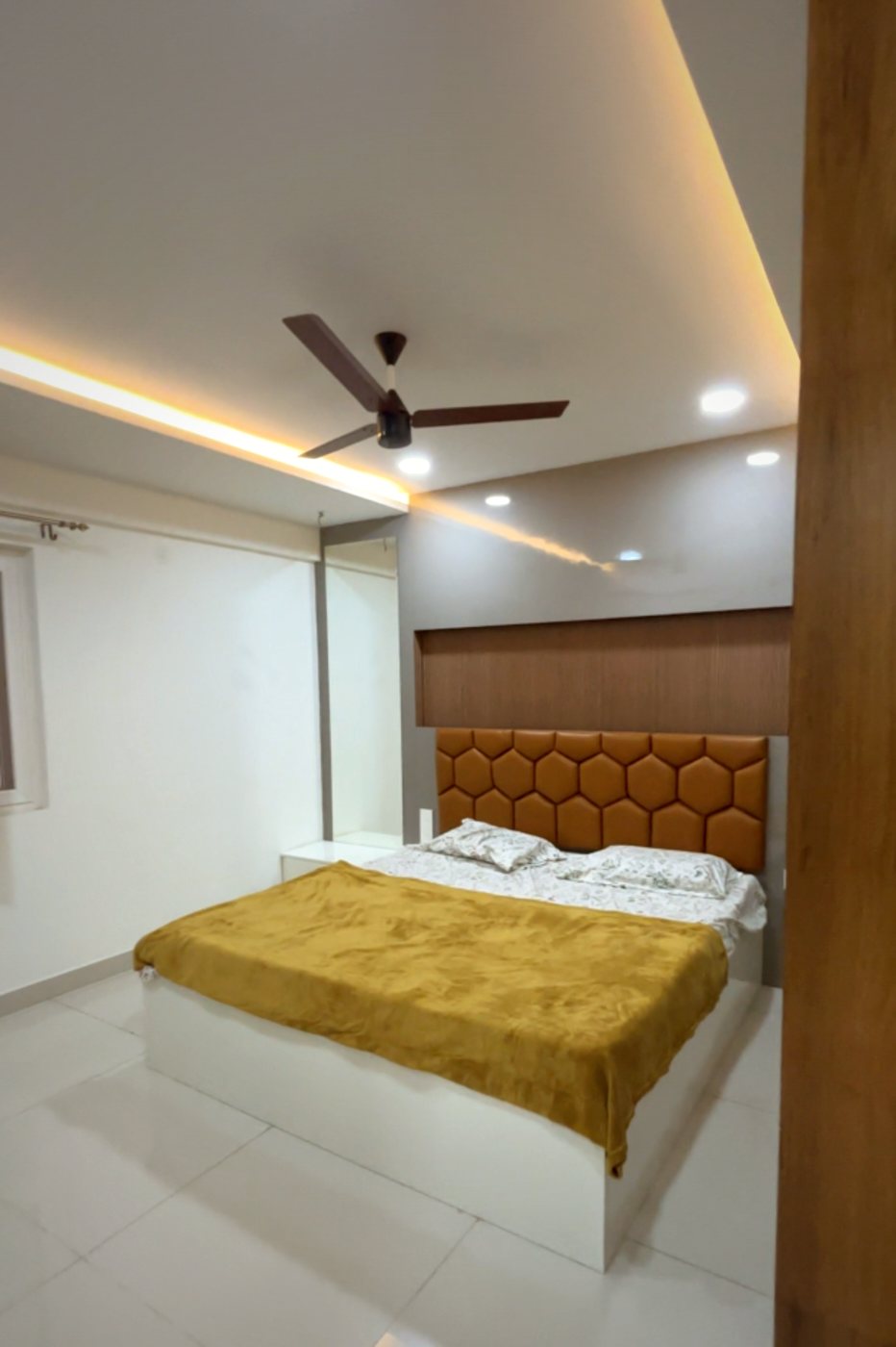 Bedroom with a hexagon-tufted headboard and cove-lit false ceiling